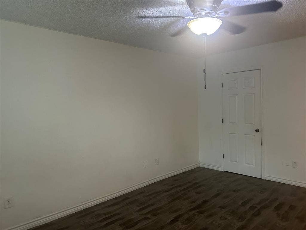1314 Frio Lane, Garland, TX 75040 Room featuring wood-finish flooring, a six-panel interior door, and a ceiling-mounted light fixture with a fan