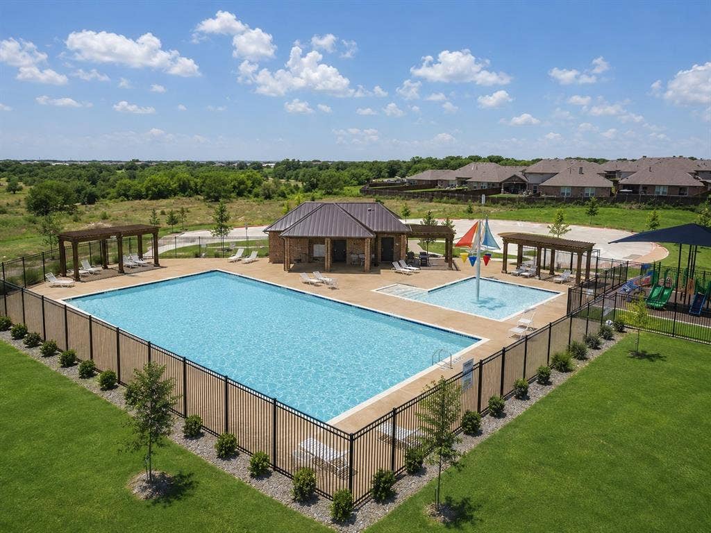 Community pool area featuring a large swimming pool, a separate wading pool with a water feature, a covered pavilion with a metal roof, and multiple shaded pergolas