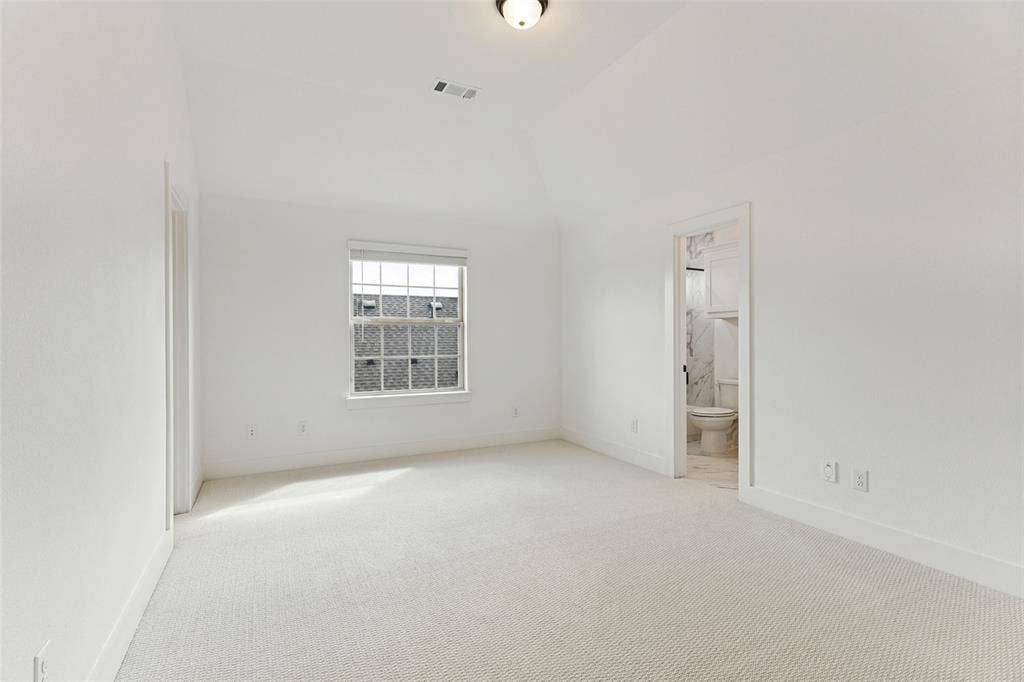 Vaulted ceilings, neutral carpeting, and a single-hung window with a blind