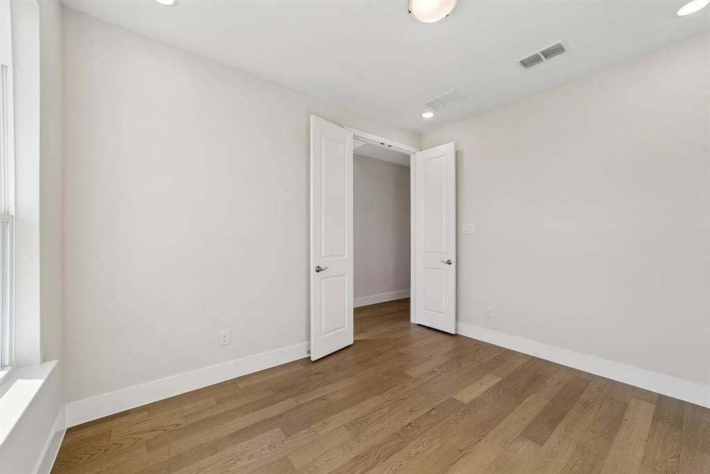 Room featuring wood-finish flooring, recessed lighting, and white two-panel interior doors