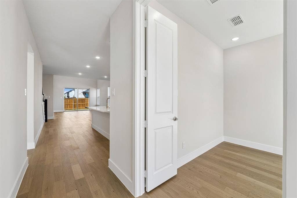 Neutral-toned interior featuring wood-finish flooring, recessed lighting, and a crisp white panel door