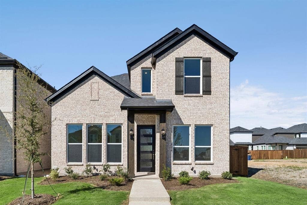 Two-story brick exterior featuring a multi-gabled roofline, dark-toned shutters, a covered entry with heavy timber-style posts, and a modern glass-panel front door