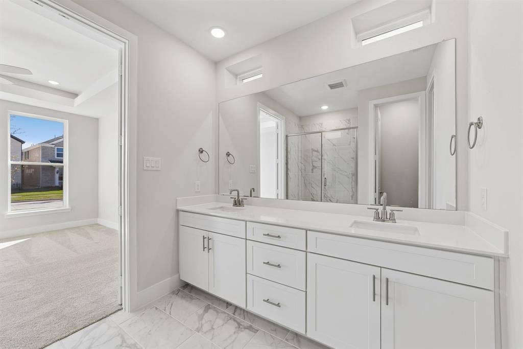 Double vanity featuring white cabinetry, stone-finish countertops, undermount sinks, and a full-width mirror with clerestory windows