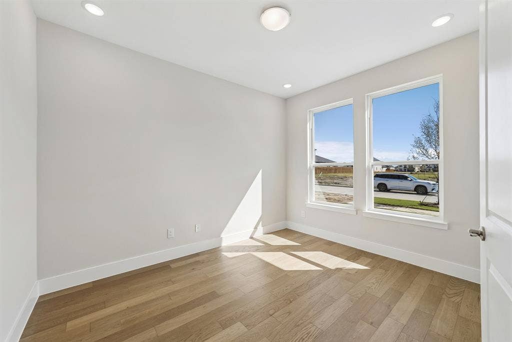 Neutral-toned interior featuring wood-finish flooring, dual windows, recessed lighting, and a flush-mount ceiling light