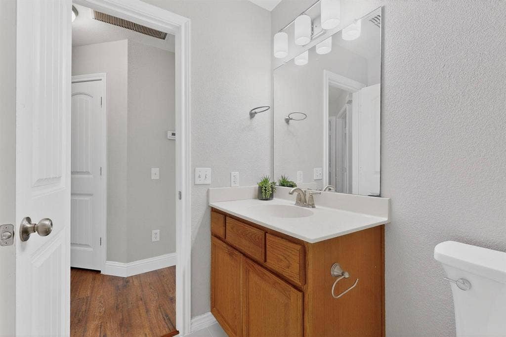 4803 Silver Avenue, Dallas, TX 75223 Bathroom featuring a wooden vanity with a white countertop, an integrated sink, a full-wall mirror, and multi-bulb light fixture