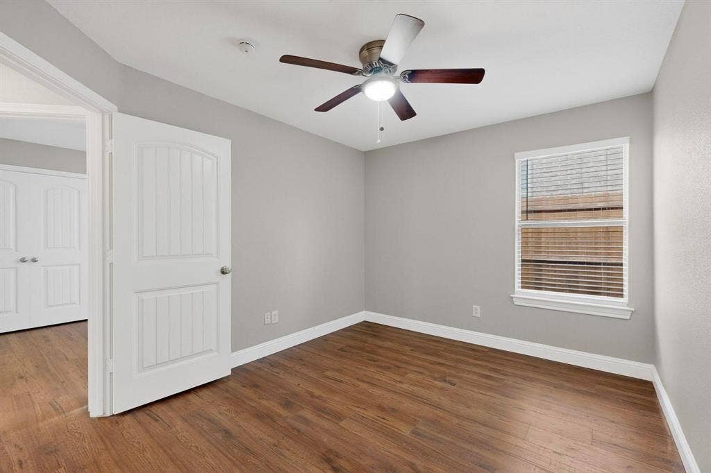 4803 Silver Avenue, Dallas, TX 75223 Room featuring wood-finish flooring, a neutral paint palette, a single-hung window with blinds, and a multi-blade ceiling fan with integrated light fixture