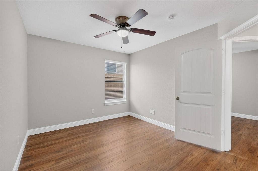 4803 Silver Avenue, Dallas, TX 75223 Room featuring wood-finish flooring, neutral wall paint, a ceiling fan with integrated lighting, and an arched two-panel interior door