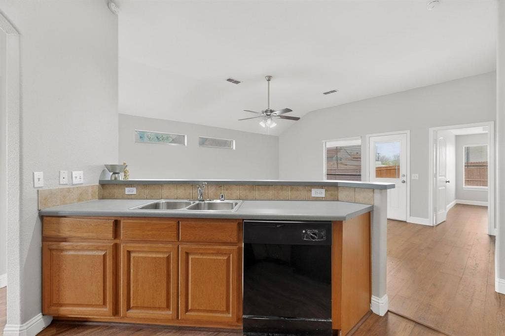 4803 Silver Avenue, Dallas, TX 75223 Kitchen featuring wood cabinetry, solid-surface countertops, a dual-basin stainless steel sink, and wood-finish flooring throughout the home