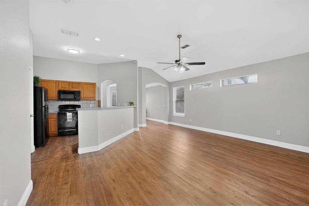 4803 Silver Avenue, Dallas, TX 75223 Open-concept interior featuring wood-finish flooring, vaulted ceilings, arched entryways, clerestory windows, and built-in cabinetry