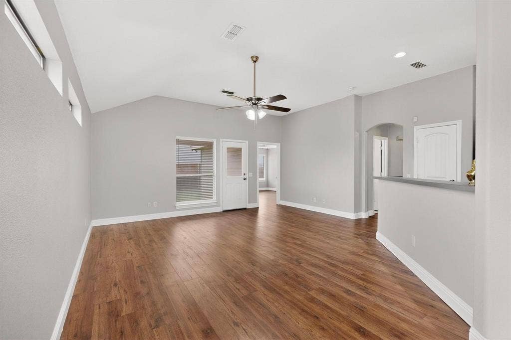 4803 Silver Avenue, Dallas, TX 75223 Vaulted ceiling featuring a central light-integrated ceiling fan, wood-finish flooring, clerestory windows, and a partial-height partition wall