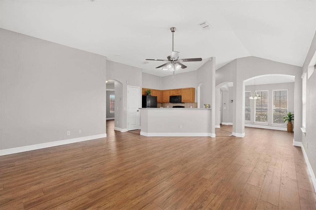4803 Silver Avenue, Dallas, TX 75223 Open-concept interior featuring vaulted ceilings, wood-finish flooring, a breakfast bar, and large windows with arched architectural detailing