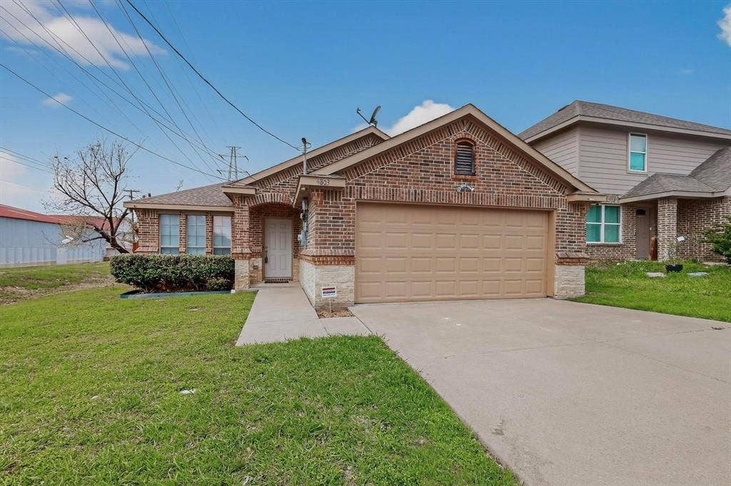 4803 Silver Avenue, Dallas, TX 75223 Single-story exterior featuring a brick facade with stone detailing, a gabled roofline, and an attached two-car garage