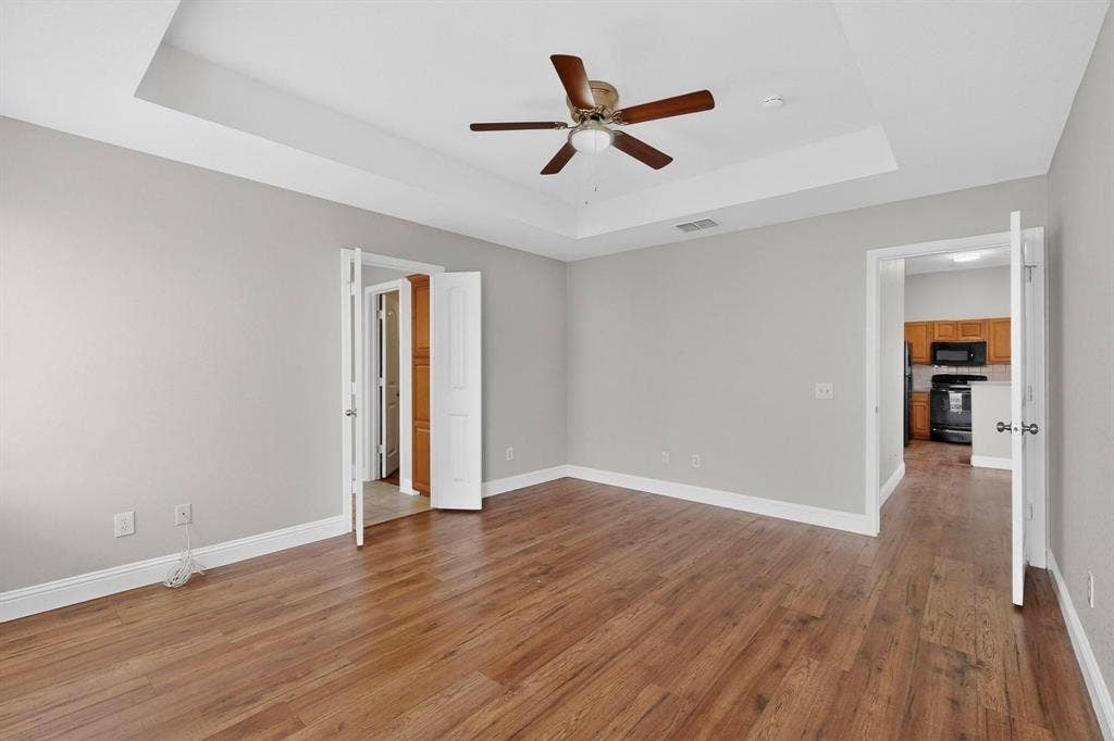 4803 Silver Avenue, Dallas, TX 75223 Tray ceiling with a central multi-blade ceiling fan, wood-finish flooring, and dual-door entries