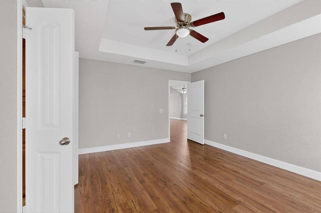 4803 Silver Avenue, Dallas, TX 75223 Room featuring wood-finish flooring, a tray ceiling, and a ceiling fan with light fixture