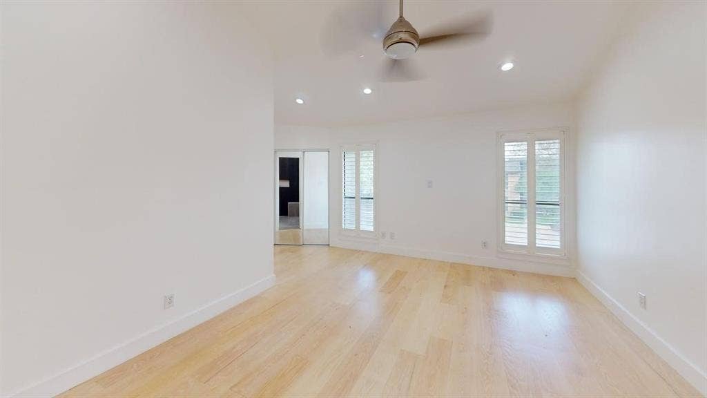 Light-filled interior featuring wood-finish flooring, recessed lighting, a ceiling fan, dual-panel interior shutters, and mirrored closet doors