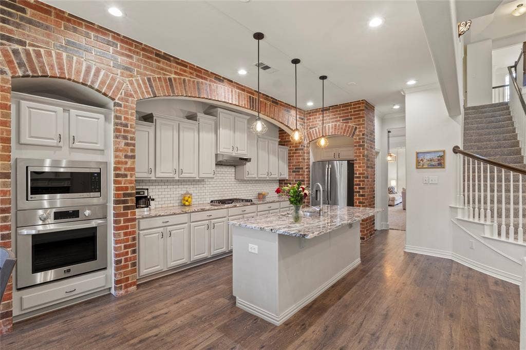 Brick accent wall, neutral granite countertop, open floorplan