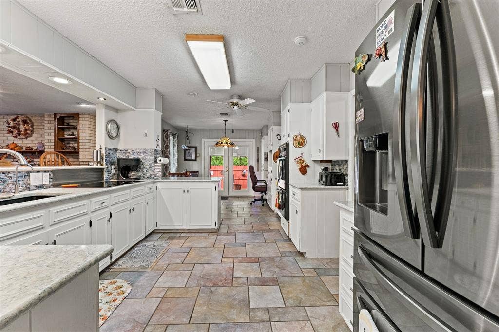 Kitchen featuring white cabinetry, stone-finish countertops, stainless steel refrigerator, and ceramic tile flooring