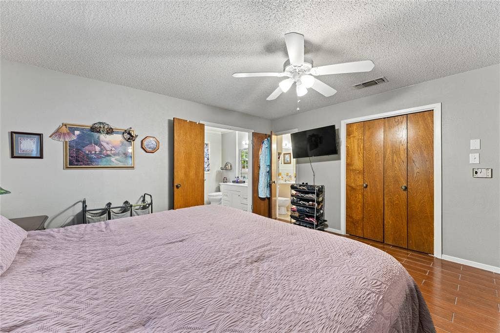 Room featuring wood-finish flooring, a ceiling fan with integrated lighting, and wooden bi-fold closet doors