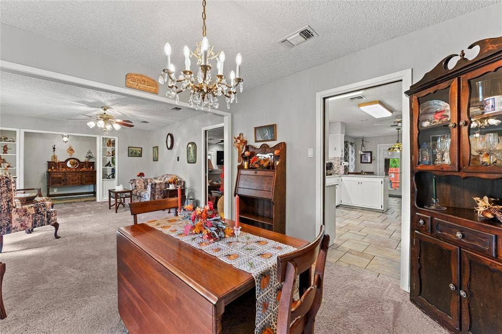 Dining area featuring a crystal-style chandelier and built-in shelving, highlighted by light-toned wall finishes and carpeting