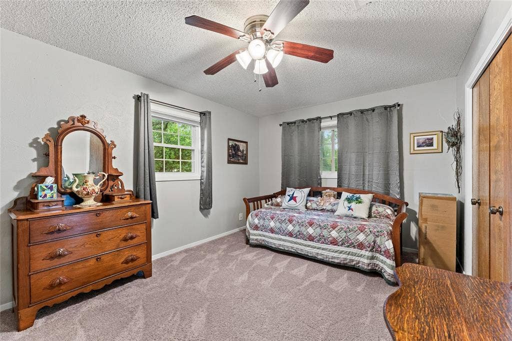 Bedroom featuring neutral wall paint, carpeted flooring, a ceiling fan with integrated lighting, and dual wood-finish closet doors