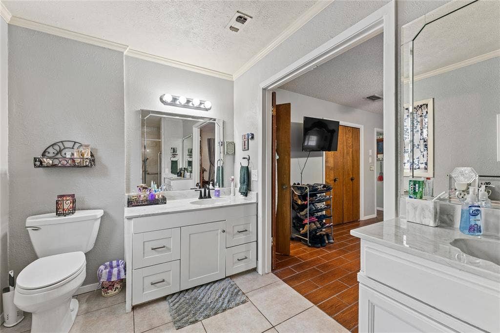 Dual white vanities featuring stone-style countertops, rectangular undermount sinks, and wall-mounted vanity lighting