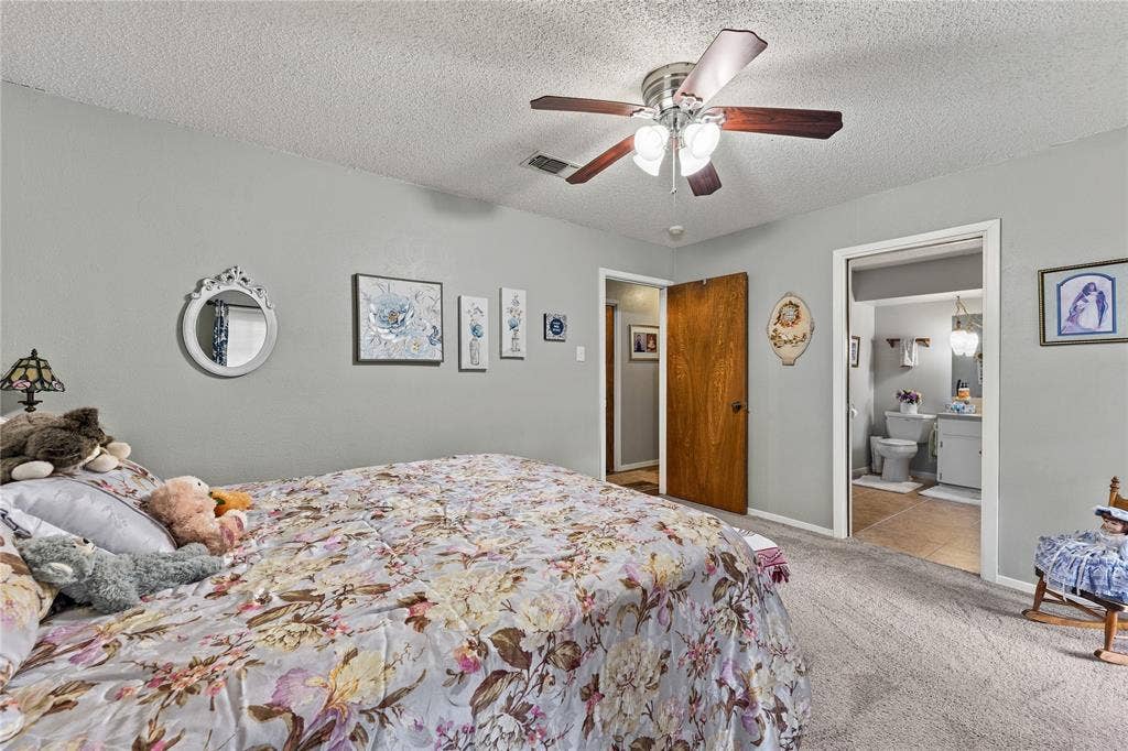 Room featuring neutral-toned walls, a central ceiling fan with multi-light fixture, carpeted flooring, and a solid wood interior door