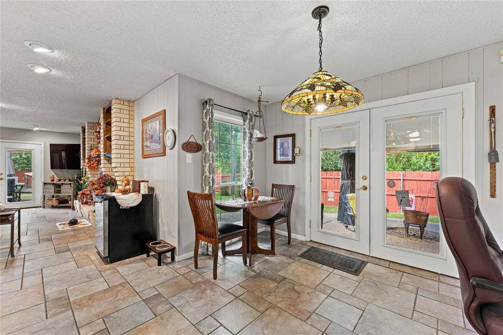 Multi-format tile flooring, exposed brick masonry, stained-glass pendant lighting, and double glass-paned doors