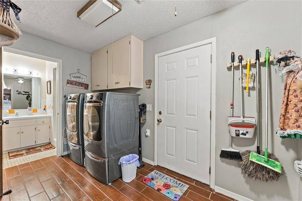 Utility room featuring wood-finish tile flooring, overhead cabinetry, and a six-panel exterior door