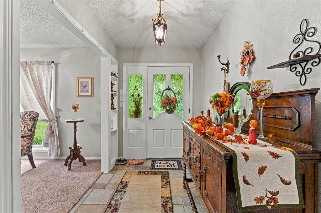 Entryway featuring a white door with decorative textured glass inserts, multi-tonal ceramic tile flooring, built-in shelving, and a hanging metal lantern light fixture