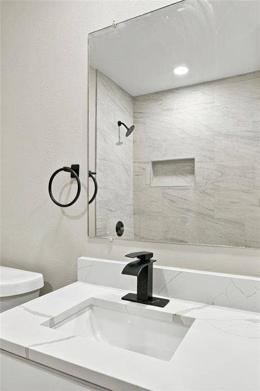 Bathroom featuring a white vanity with a stone-finish countertop, undermount sink, matte black waterfall faucet, and large wall-mounted mirror