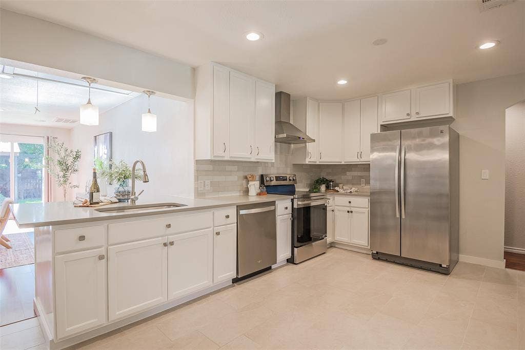 8050 Fall River Drive, Dallas, TX 75228 Kitchen featuring white shaker-style cabinetry, stainless steel appliances, a stone-composite countertop with an undermount sink, recessed lighting, and a subway-tile backsplash