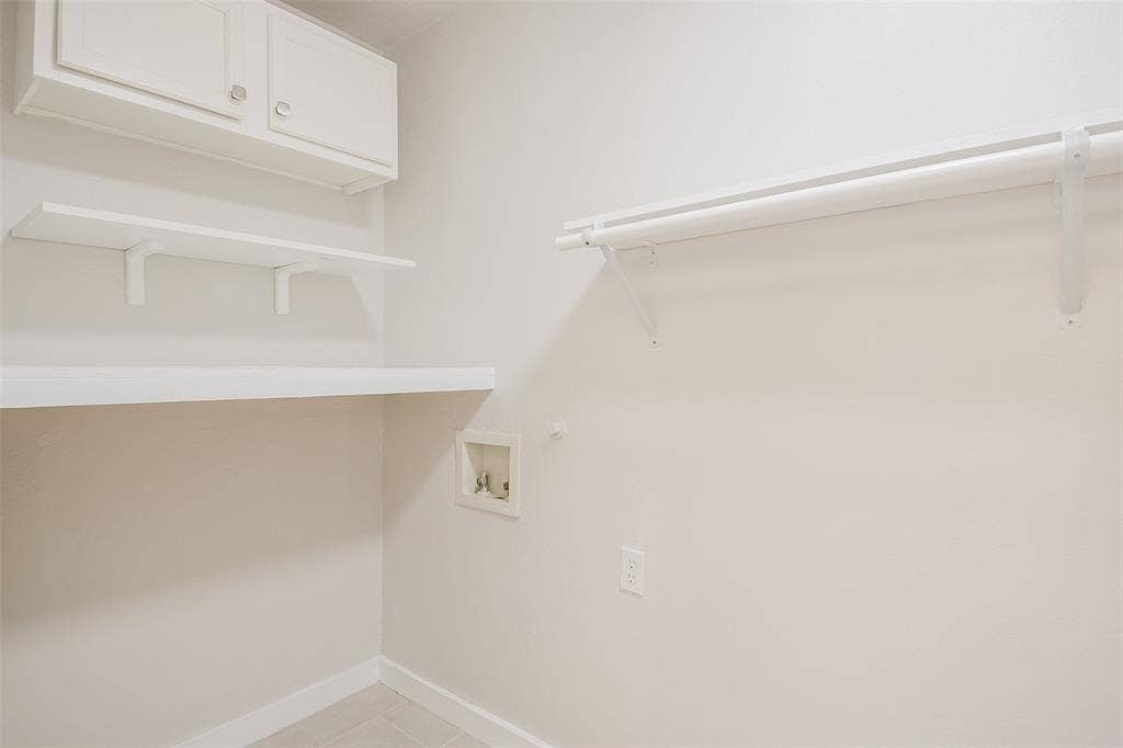 8050 Fall River Drive, Dallas, TX 75228 Wall-mounted white cabinetry, open shelving, and a metal clothing rod with integrated support brackets