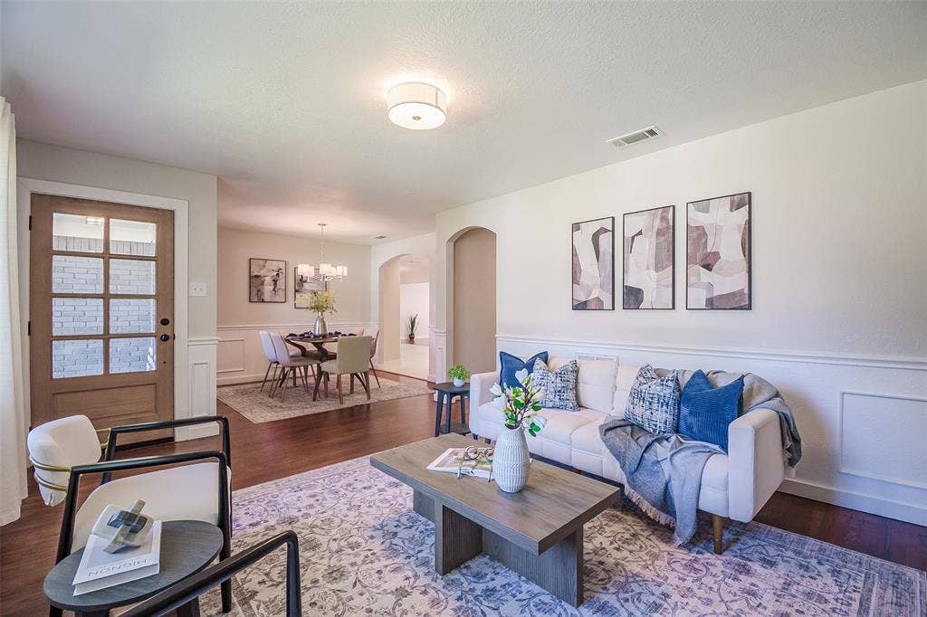 8050 Fall River Drive, Dallas, TX 75228 Wood-finish flooring, multi-pane glass entry door, arched interior doorway, and wainscoting