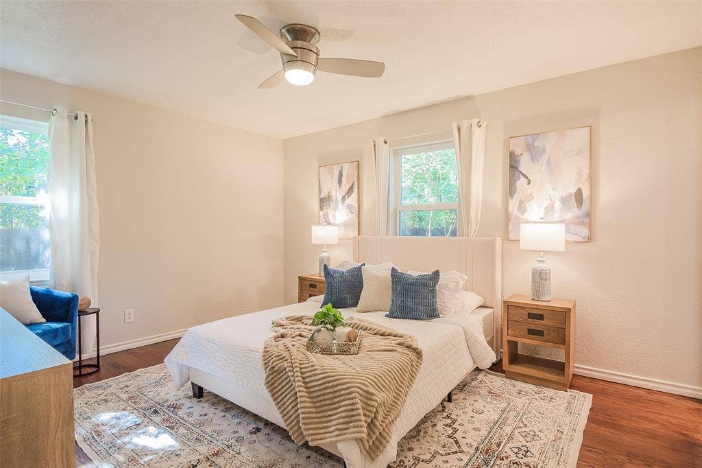 8050 Fall River Drive, Dallas, TX 75228 Room featuring wood-finish flooring, neutral wall paint, two dual-pane windows, and a brushed nickel ceiling fan with integrated lighting