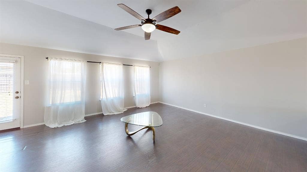 Vaulted ceilings, wood-finish flooring, and a central ceiling fan with integrated lighting