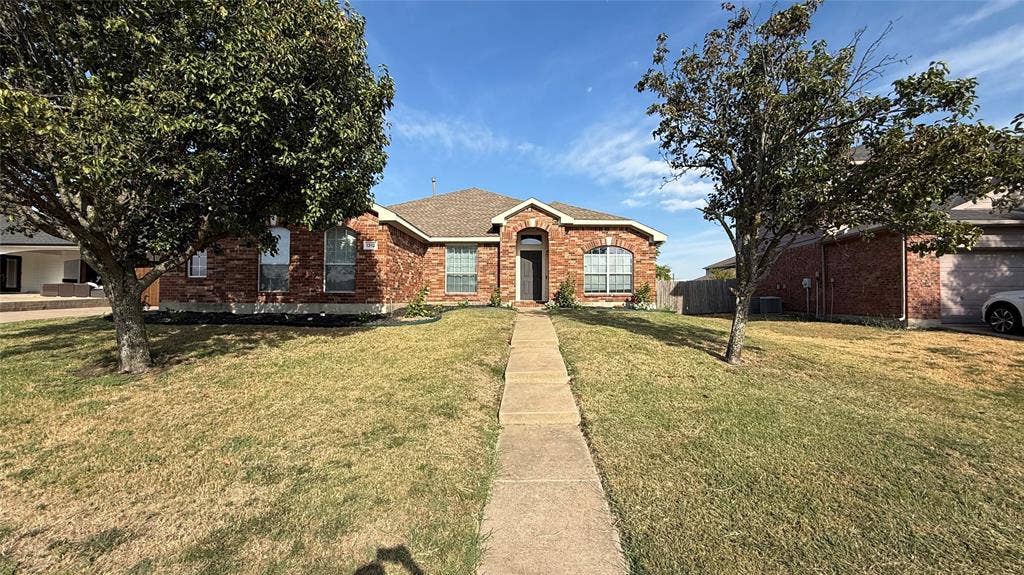 Traditional brick exterior featuring arched window detailing, a covered entryway, and mature trees