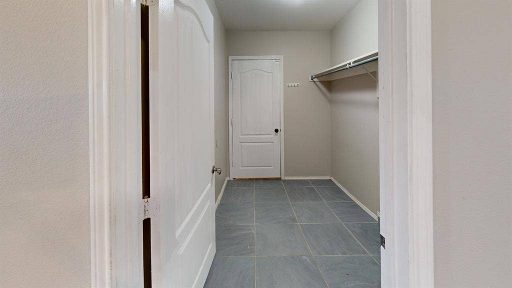 Large-format tile flooring, arched two-panel interior door, and integrated wall-mounted storage shelving