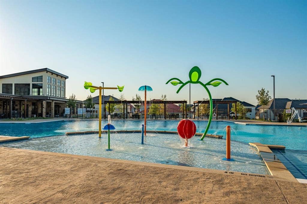 LEXINGTON Community Swimming pool with a zero-entry splash pad featuring colorful water spray fixtures and a textured concrete deck