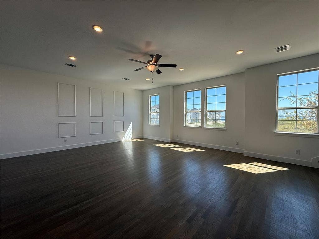 9223 Easy Street, Rowlett, TX 75088 Spacious interior featuring wood-finish flooring, wainscoting wall detailing, multiple grid-pattern windows, and a central ceiling fan