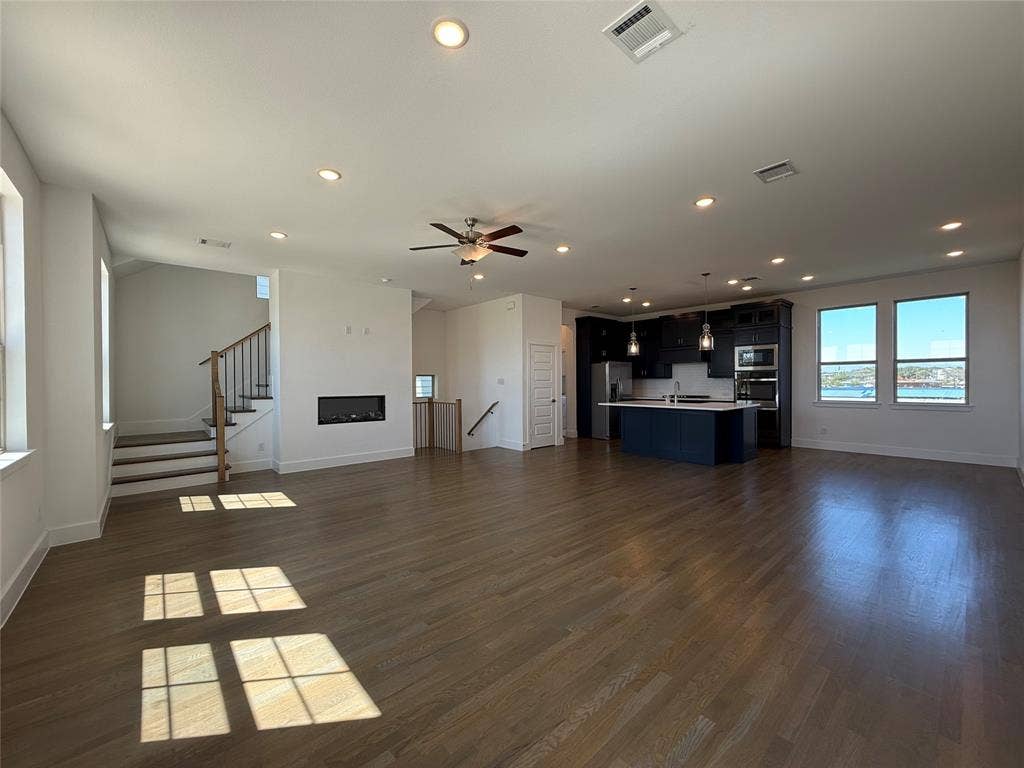 9223 Easy Street, Rowlett, TX 75088 Open-concept interior featuring wood-finish flooring, a contemporary linear fireplace, and kitchen cabinetry with a contrasting center island