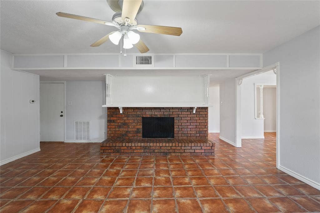 9214 Vagas Drive, Rowlett, TX 75088 Unfurnished living room featuring dark tile floors, ceiling fan, and a brick fireplace