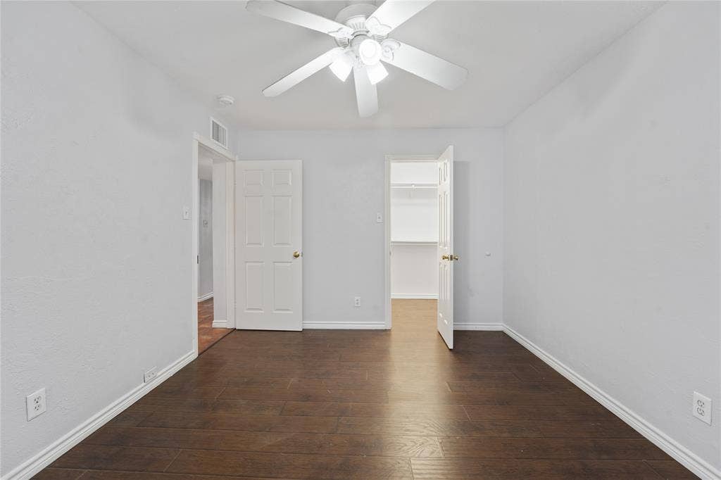9214 Vagas Drive, Rowlett, TX 75088 Unfurnished bedroom with a closet, ceiling fan, dark hardwood / wood-style flooring, and a spacious closet