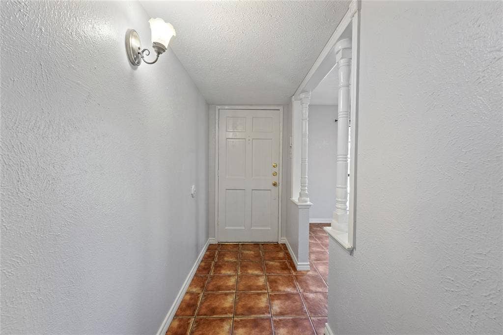 9214 Vagas Drive, Rowlett, TX 75088 Hallway with a textured ceiling and dark tile flooring