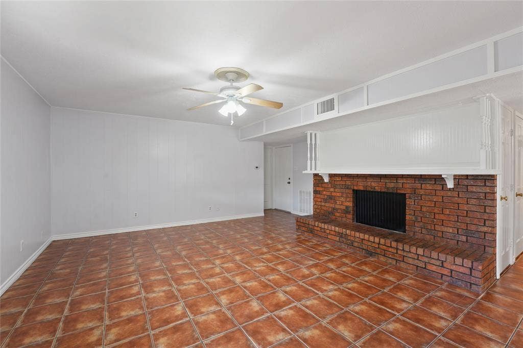 9214 Vagas Drive, Rowlett, TX 75088 Unfurnished living room with dark tile flooring, a brick fireplace, and ceiling fan