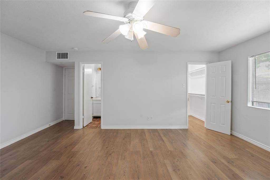 9214 Vagas Drive, Rowlett, TX 75088 Unfurnished bedroom featuring wood-type flooring, ceiling fan, a walk in closet, and ensuite bathroom