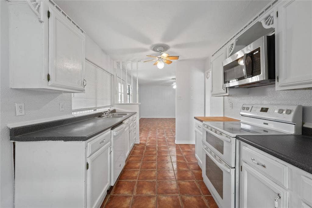 9214 Vagas Drive, Rowlett, TX 75088 Kitchen with ceiling fan, dark tile floors, white cabinets, sink, and white appliances