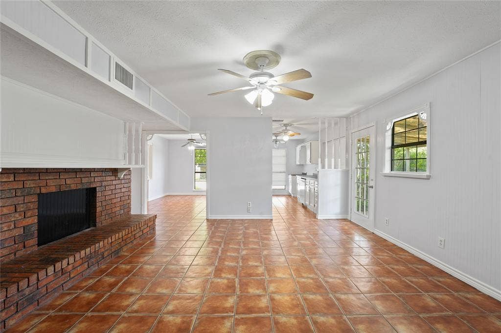 9214 Vagas Drive, Rowlett, TX 75088 Unfurnished living room featuring tile floors, ceiling fan, and a fireplace