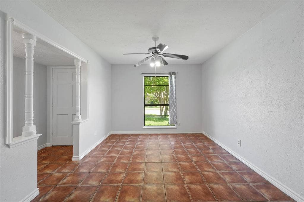 9214 Vagas Drive, Rowlett, TX 75088 Unfurnished room with dark tile floors, ornate columns, and ceiling fan