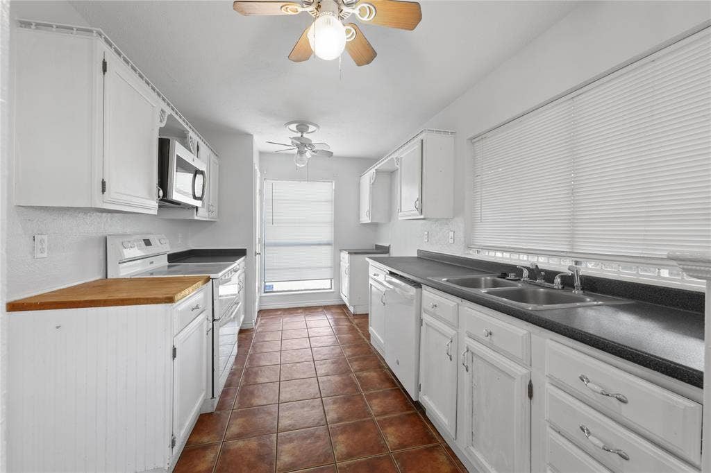 9214 Vagas Drive, Rowlett, TX 75088 Kitchen with white cabinetry, dark tile floors, ceiling fan, and white appliances