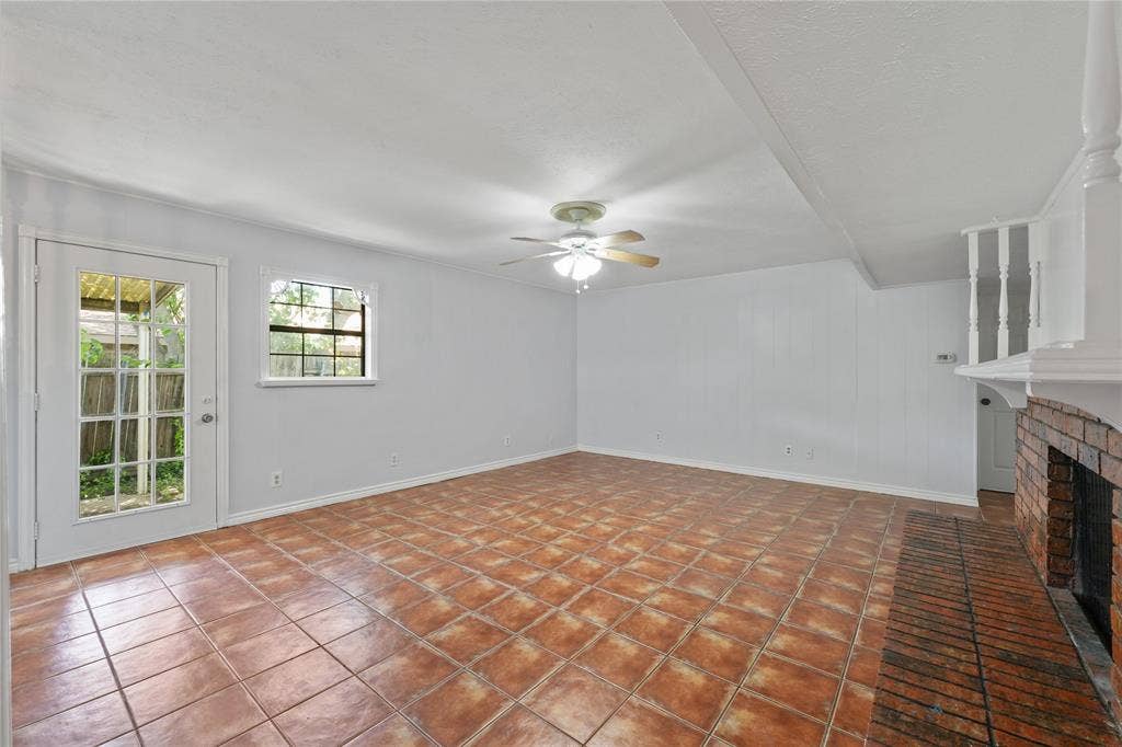 9214 Vagas Drive, Rowlett, TX 75088 Unfurnished living room featuring a brick fireplace, ceiling fan, and tile flooring